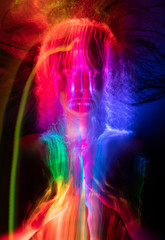 Conceptual avant-garde portrait of a beautiful young girl covered with multicolored lines applied by a light brush. Art style creative photo. Advertising, fashion and commercial design.
