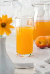 Glass with apricot juice and vase with flower