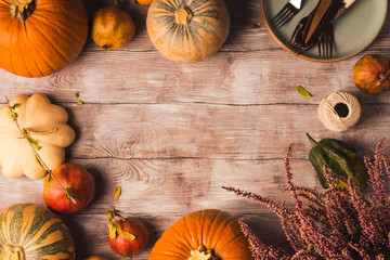 Autumn thanksgiving background with pumpkins, fall fruit and tableware for dinner.
