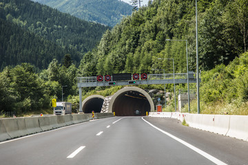 Autobahn or highway with a bridge in the mountains with clear marking surrounded by vibrant green...