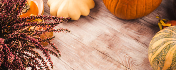 Autumn thanksgiving moody background with different pumpkins, fall fruit and flowers on rustic wooden table.