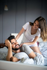 Happy young couple making massage in bedroom