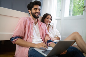 Young couple relaxing on bed with laptop. Love, technology, happiness, people and fun concept.