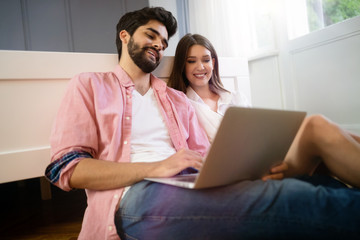 Young couple relaxing on bed with laptop. Love, technology, happiness, people and fun concept.