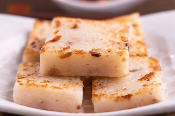 Delicious turnip cake, Chinese traditional local dish radish cake in restaurant with soy sauce and chopsticks, close up, copy space.