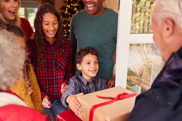 Grandparents Arriving With Gifts To Celebrate Multi-Generation Family Christmas At Home