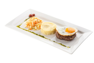Fried egg with beefsteak, mashed potatoes and pickled cabbage on white plate isolated on white background