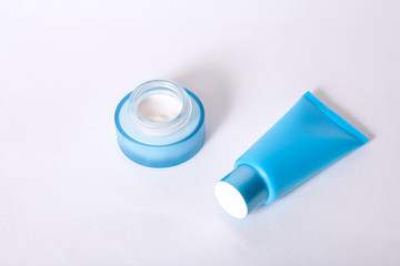 tube with moisturizing mask blue and a jar of cream blue on a white background