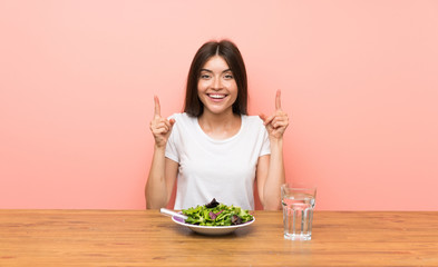 Young woman with a salad pointing up a great idea