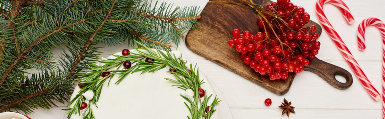 top view of christmas pie and viburnum berries on white wooden table with spruce branches