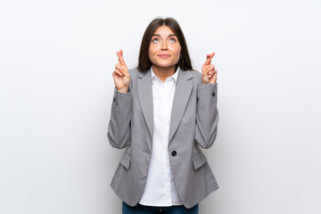 Young business woman over isolated white background with fingers crossing and wishing the best