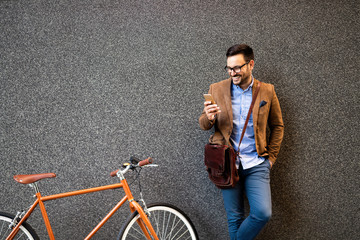 Happy businessman outside of office in urban. Young caucasian man holding smartphone for business...