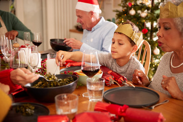 Multi-Generation Family Sitting At Dining Table Enjoying Christmas Meal At Home Together