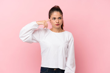 Young brunette girl over isolated pink background making the gesture of madness putting finger on...
