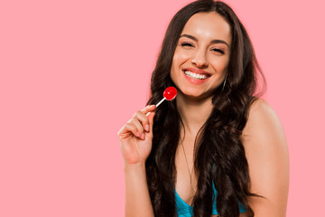 smiling woman holding red lollipop isolated on pink
