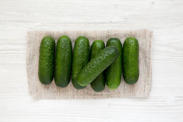 Ripe organic mini baby cucumbers on a white wooden background, top view. Flat lay, overhead, from above.