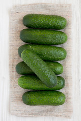 Fresh organic mini baby cucumbers on a white wooden surface, top view. Flat lay, overhead, from above. Close-up.