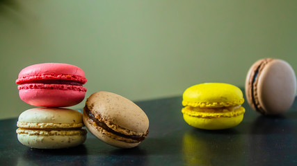 many bright macaroons cookies on a dark table