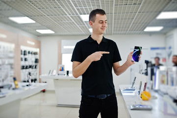 Seller man mobile phone professional consultant in tech store or shop hold new smartphone at  hand...