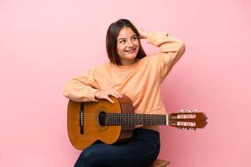 Young brunette girl with guitar over isolated pink background has realized something and intending...