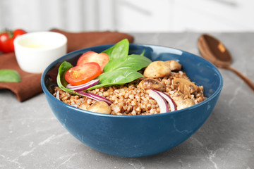 Tasty buckwheat porridge with vegetables and mushrooms on table indoors