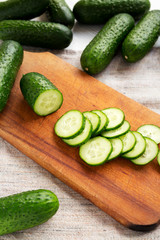 Fresh mini baby cucumbers on a rustic wooden board, low angle view. Close-up.