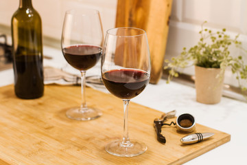 Copas de vino tinto sobre tabla de madera rústica en la cocina vista de frente
