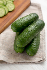Fresh mini baby cucumbers on a rustic wooden board, low angle view. Closeup.