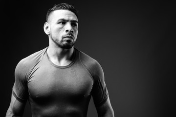 Young muscular Hispanic man against black background