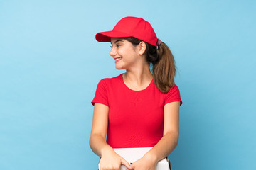 Young woman holding a pizza over isolated pink wall looking to the side