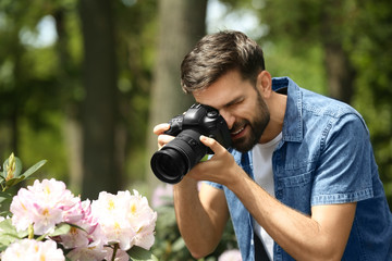 Photographer taking photo of blossoming bush with professional camera in park