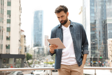 Handsome man working with tablet on city street