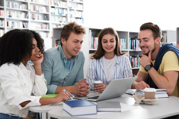 Fototapeta premium Group of young people studying at table in library