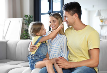 Fototapeta premium Happy family with little daughter on sofa in living room
