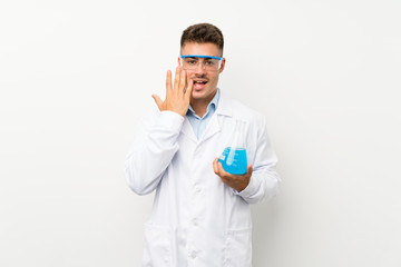 Young scientific holding laboratory flask over isolated background with surprise facial expression