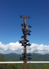 Obraz premium tourist signpost in the mountains. arrows and city names against a blue sky