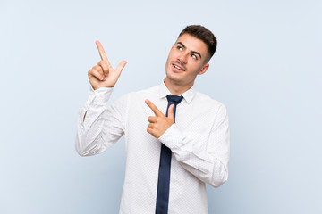 Handsome businessman over isolated blue background pointing with the index finger a great idea