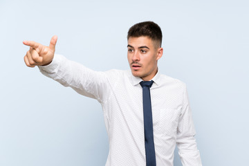 Handsome businessman over isolated blue background pointing away