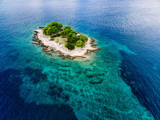 Aerial view of crystal waters and tropical island with green trees
