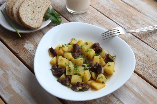 Meat and potapo  stew in white plate on wooden table
