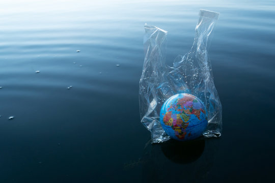 The World Or Earth Model In A Transparency Plastic Bag Floating In Dark Blue Ocean Water For Environmental Pollution Planet Protection Concept