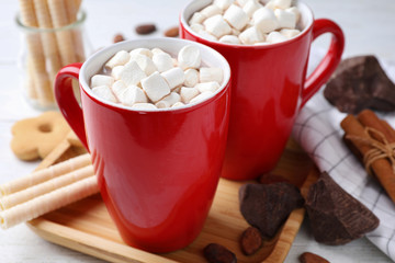 Composition of tasty cocoa with marshmallows in cups on white wooden table