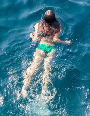 A girl swims in the blue water of the sea
