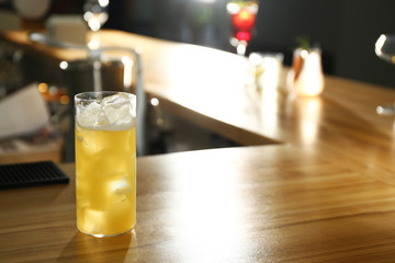 Glass of delicious cocktail with vodka on wooden counter in bar. Space for text