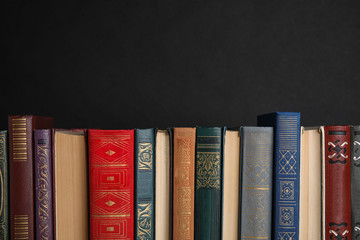 Stack of hardcover books on black background. Space for text