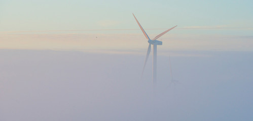 Wind turbines in a foggy field at sunrise in autumn