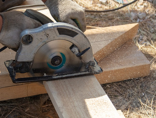 A worker cuts a wooden board at a construction site