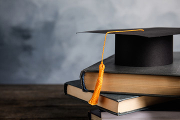Fototapeta Graduation hat, books and student's diploma on wooden table against light blue background obraz