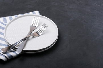 Served table for two.Plates, forks, napkin on the dark table