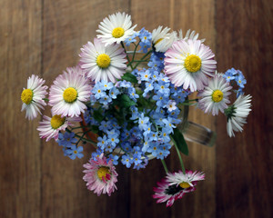 small bouquet of blue forget-me-nots and daisies on an old wooden background